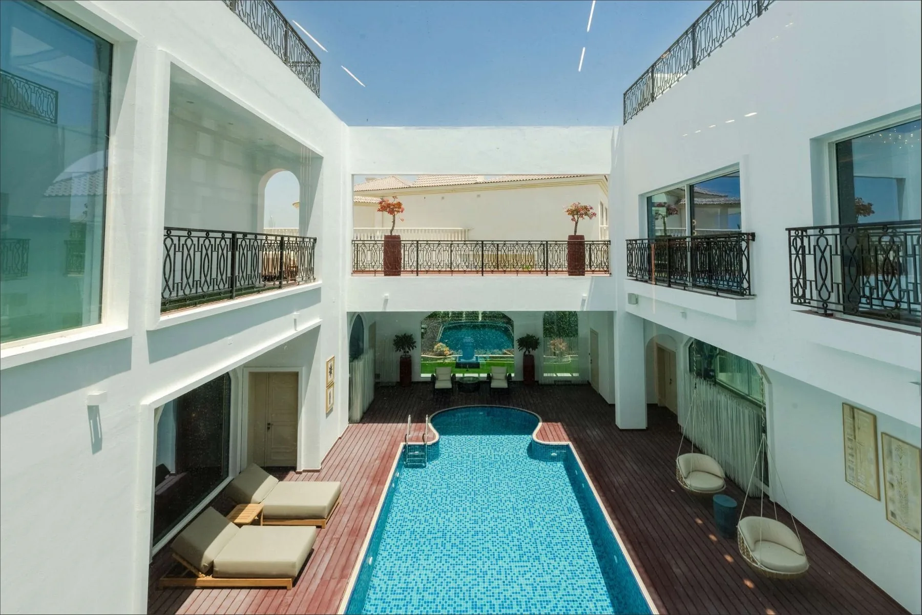 The courtyard pool seen from the first-floor balcony, with wrought-iron balustrades and loungers on the deck