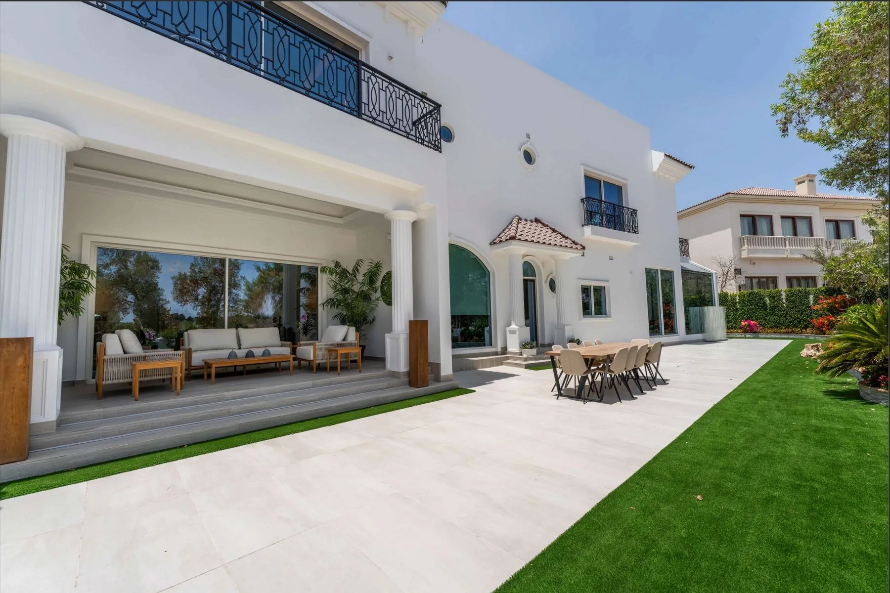 The covered terrace with outdoor dining and lounge seating beside the lawn