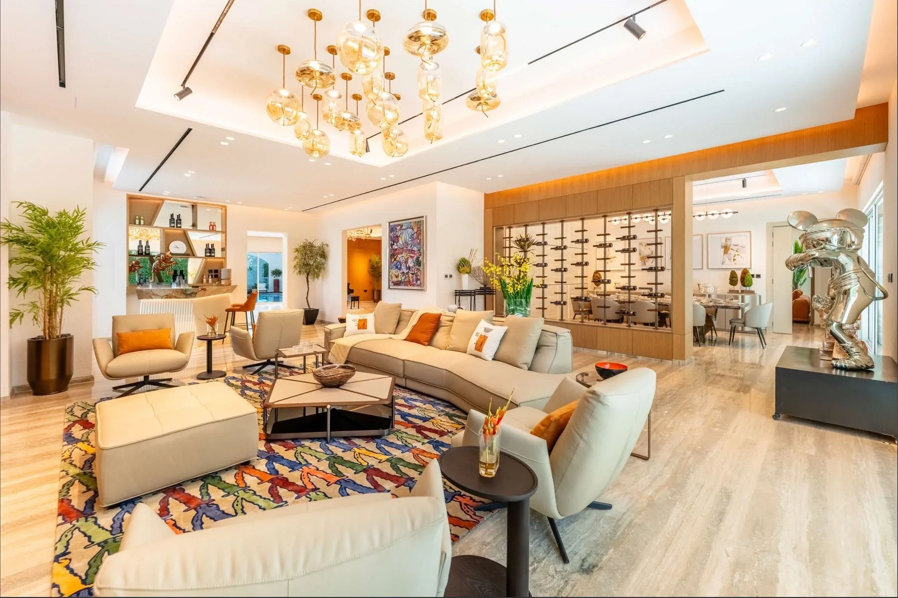 The formal majlis with a chandelier, cream seating and a patterned rug, opening onto the garden