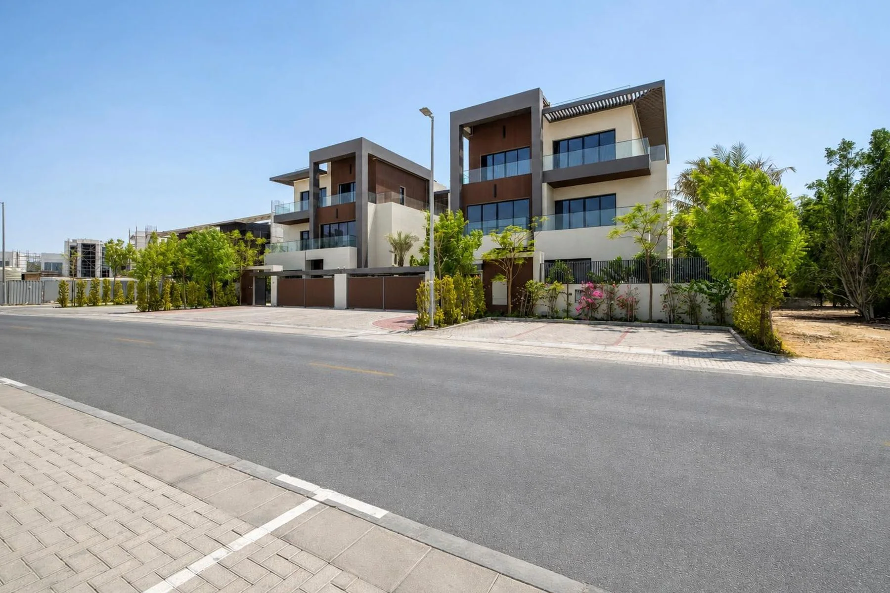 The mansion's corner elevation from the street — dark timber cladding, glass balustrades and mature landscaping