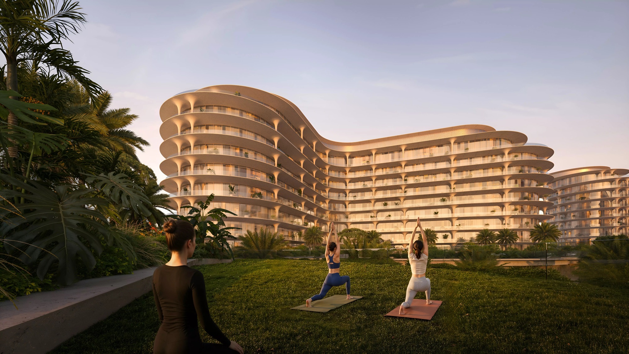 Residents practising yoga on the lawn at The Row Saadiyat below a curved golden façade at sunset