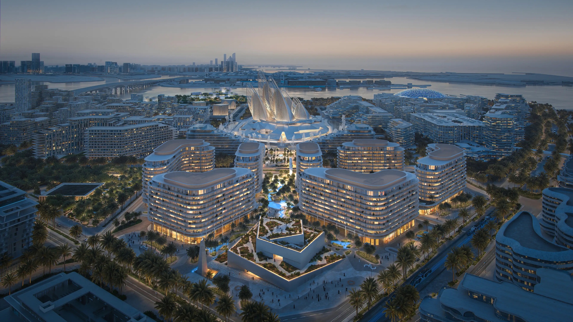The Row Saadiyat lit at night from the air, with the Zayed National Museum and the water beyond